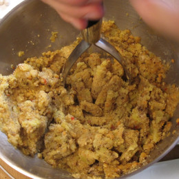 Alle Zutaten für die Malai Kofte mit einem Kartoffelstampfer zu einer festen Masse zerdrücken.
